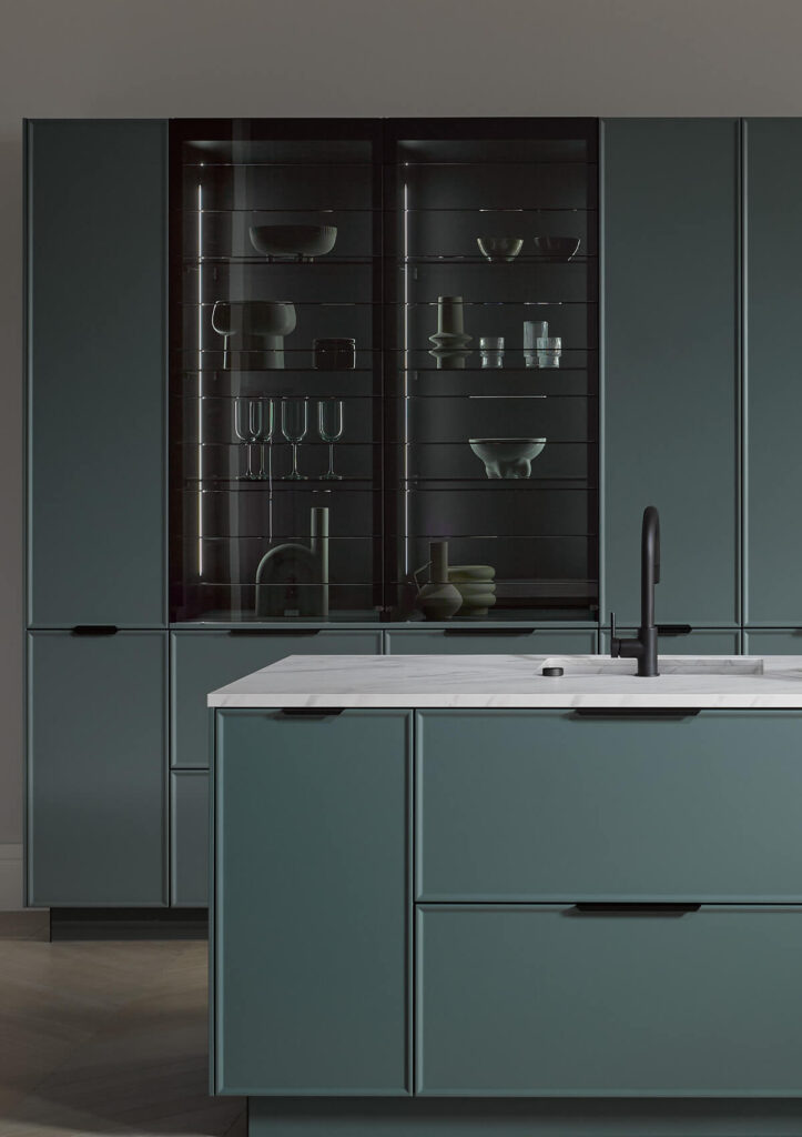 Häcker Küchen – Kochinsel in Graugrün mit schwarzer Armatur und Glasvitrine in Kristallweiß